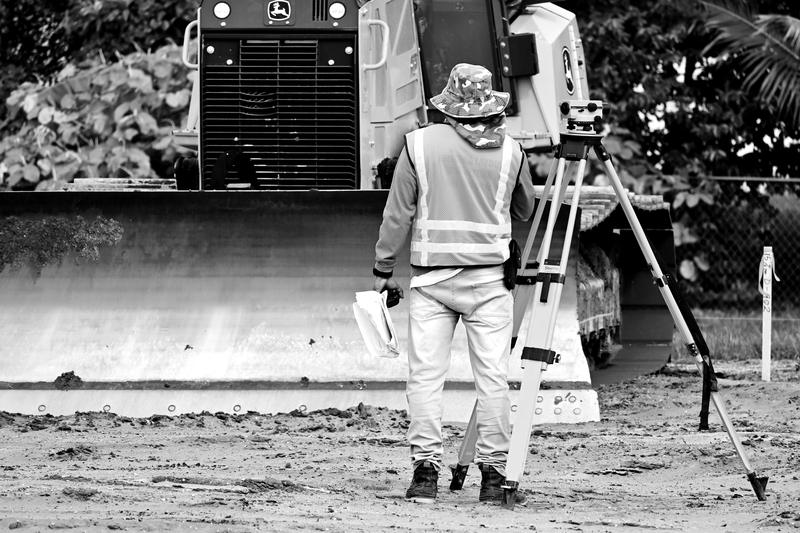 A surveyor setting up a level beside a bulldozer