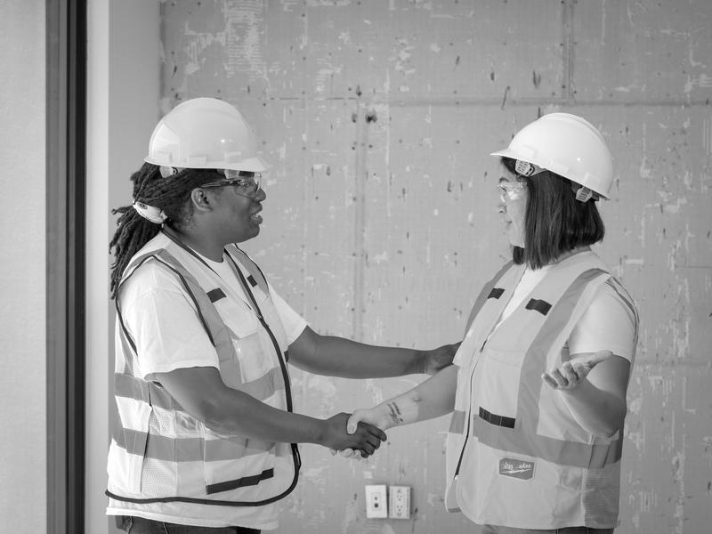 Two site managers in hard hats shaking hands