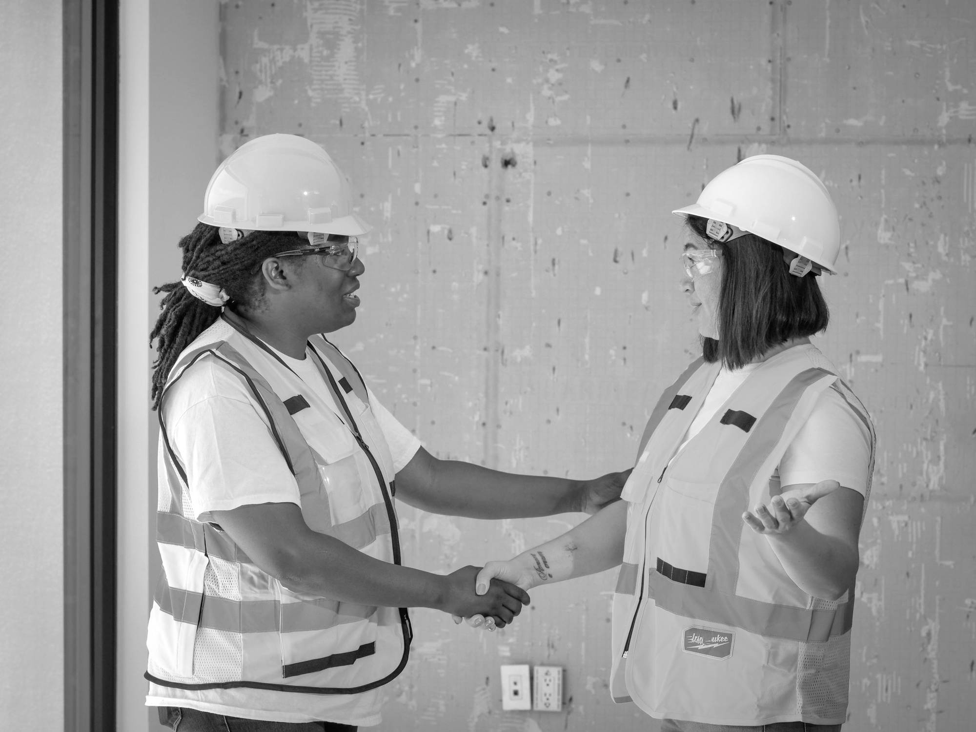 Two site managers in hard hats shaking hands