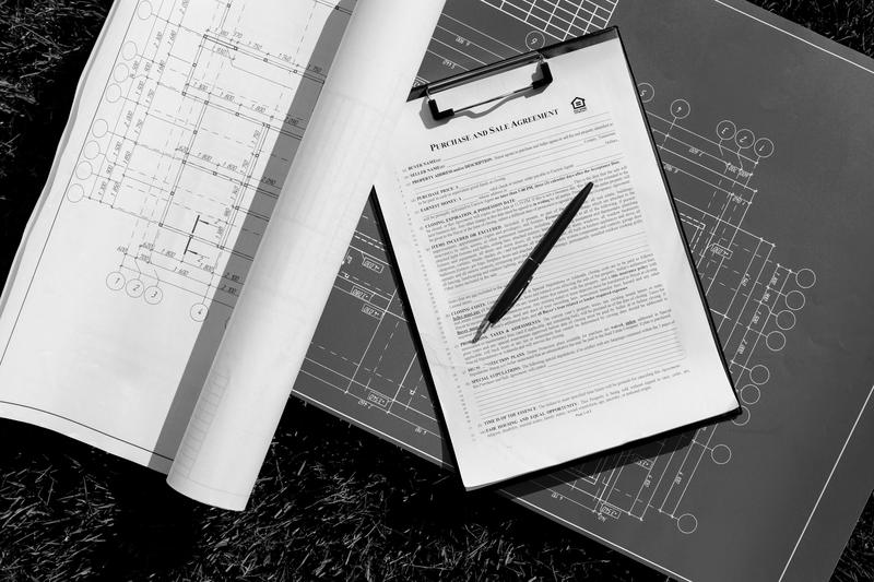 A clipboard of documents resting on blueprints